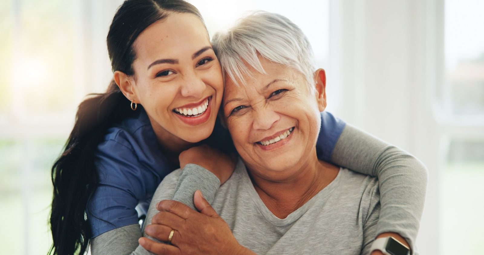 Senior Care Web Design Caregiver embracing a smiling senior woman at home
